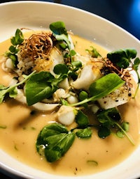 a white plate with fish and greens on it